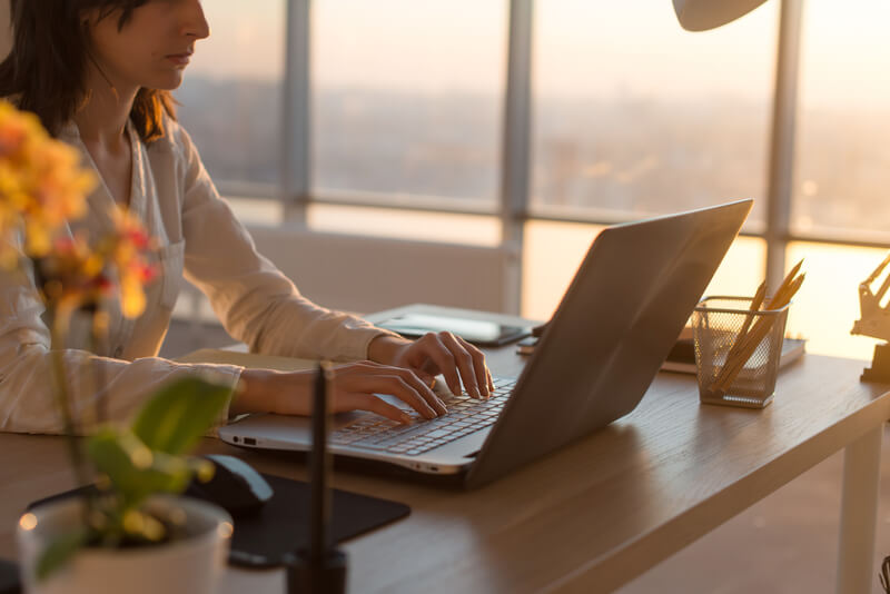 Concentrated female employee typing at workplace using computer. Side view portrait of a copywriter working on pc home