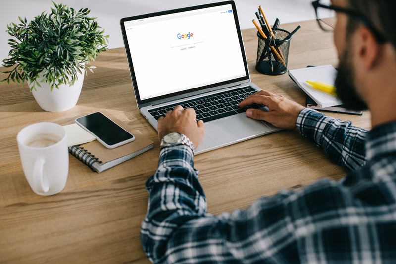 cropped shot of man in plaid shirt using laptop with google website