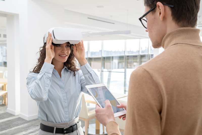 Happy young employee touching vr headset while communicating with male colleague