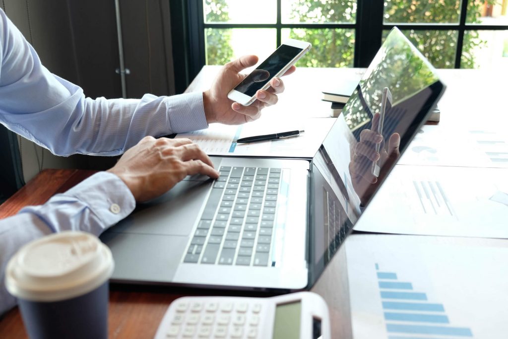 man using laptop and phone to browse the internet