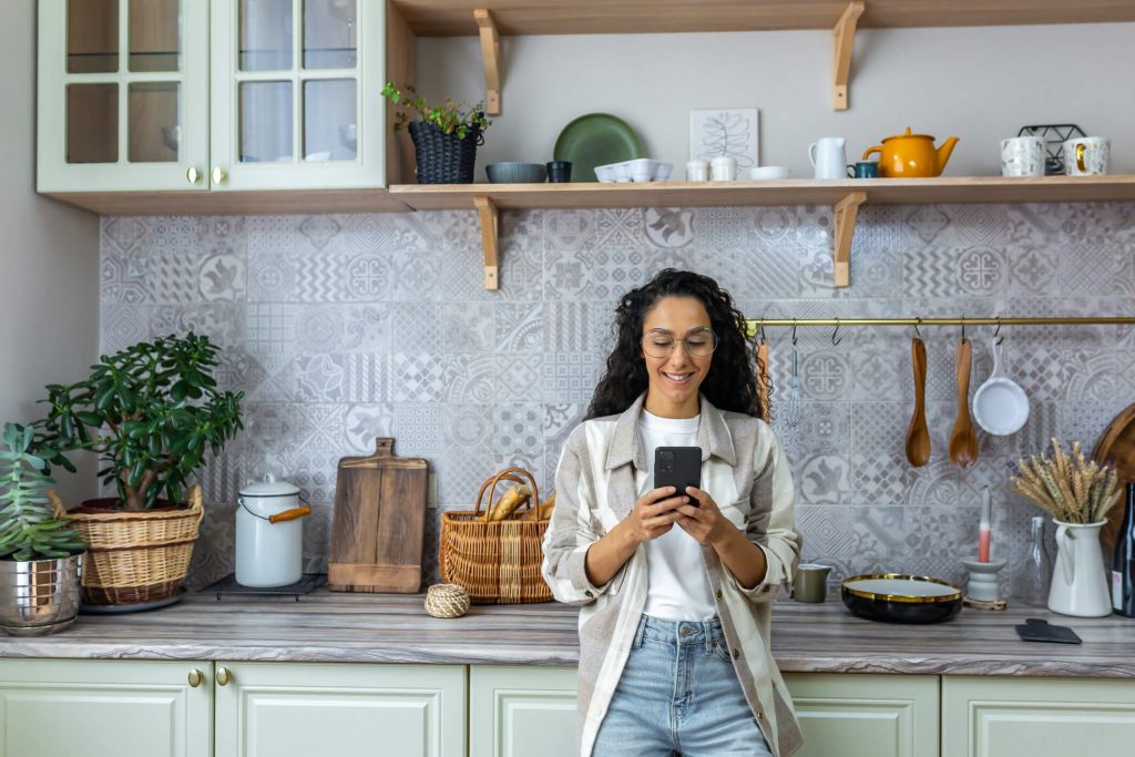 woman uses mobile phone at home in the kitchen