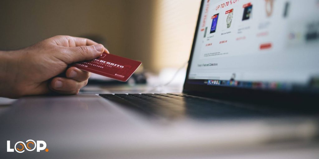 A person holding a debit card whilst looking at an ecommerce website